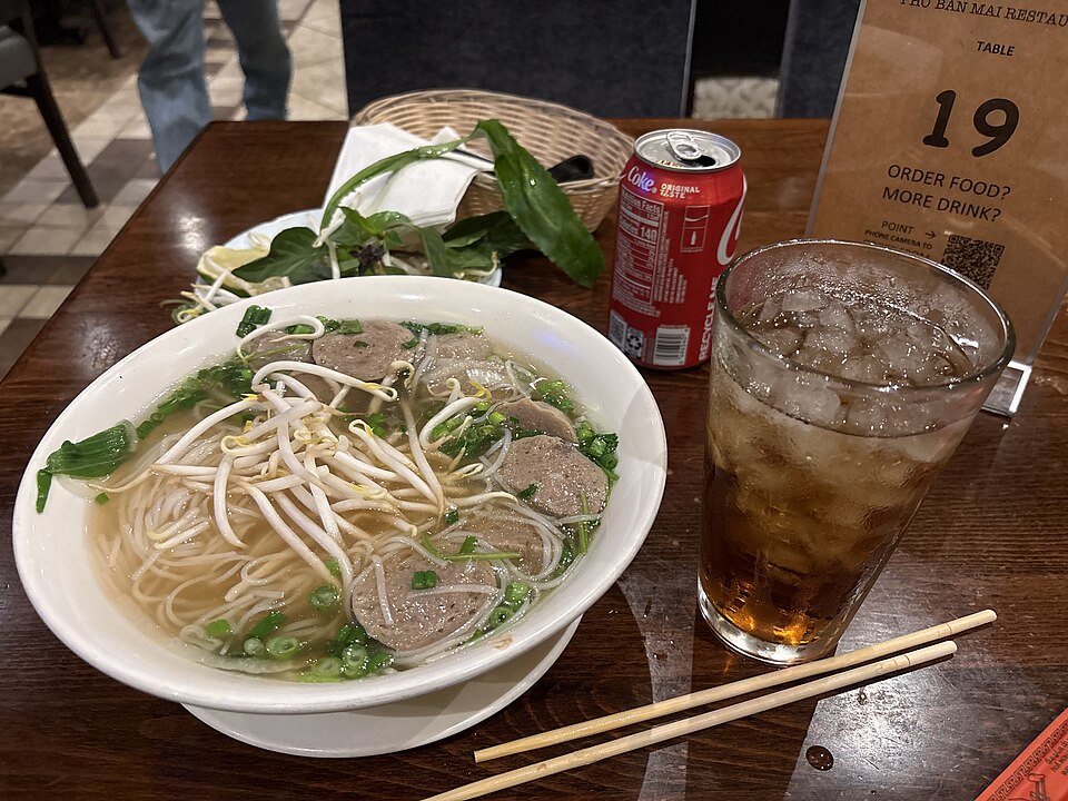 A bowl of pho with herbs
