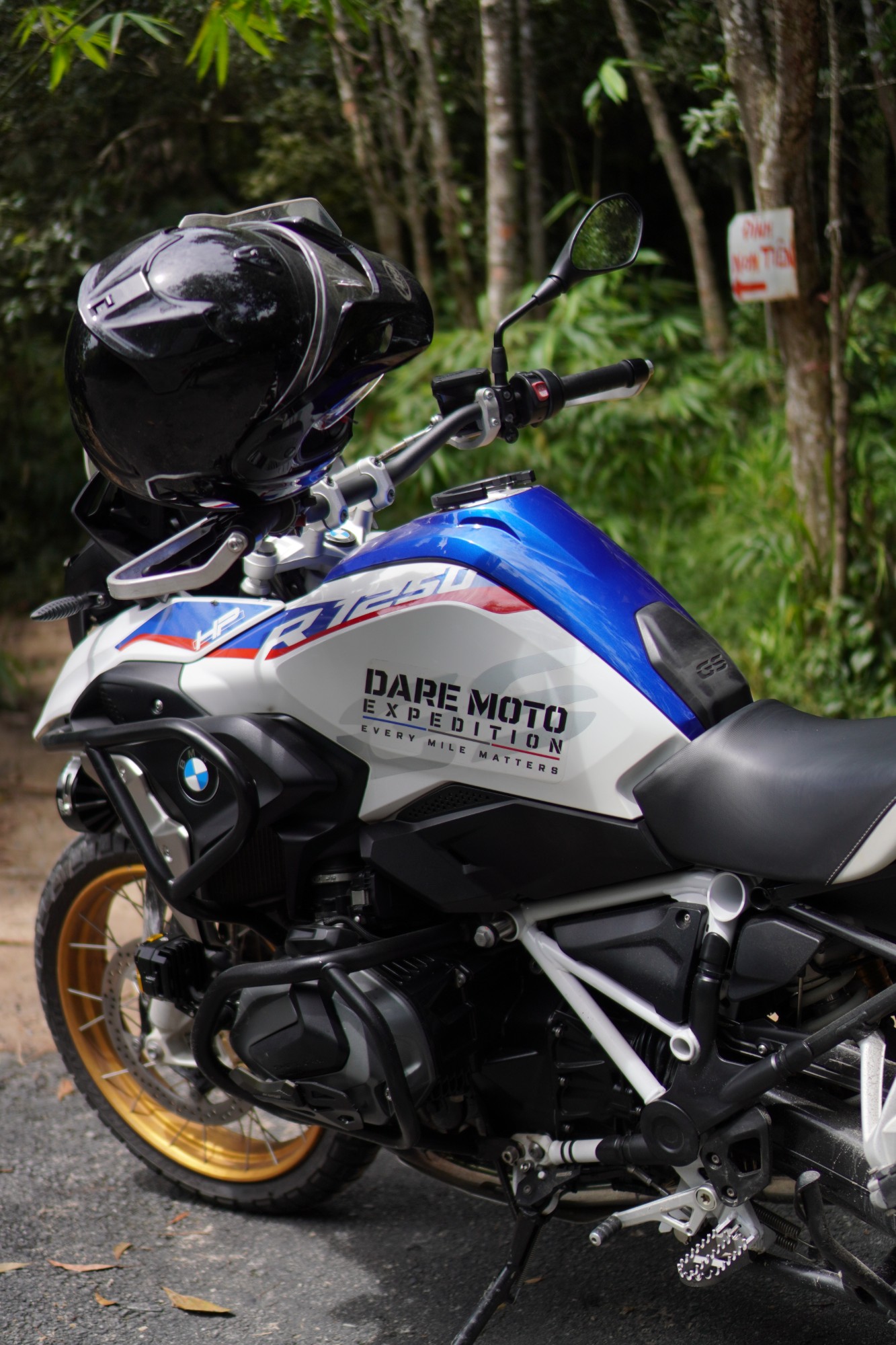 DME BMW R1250 GS HP with a helmet on the mirror, parked by a forest trail