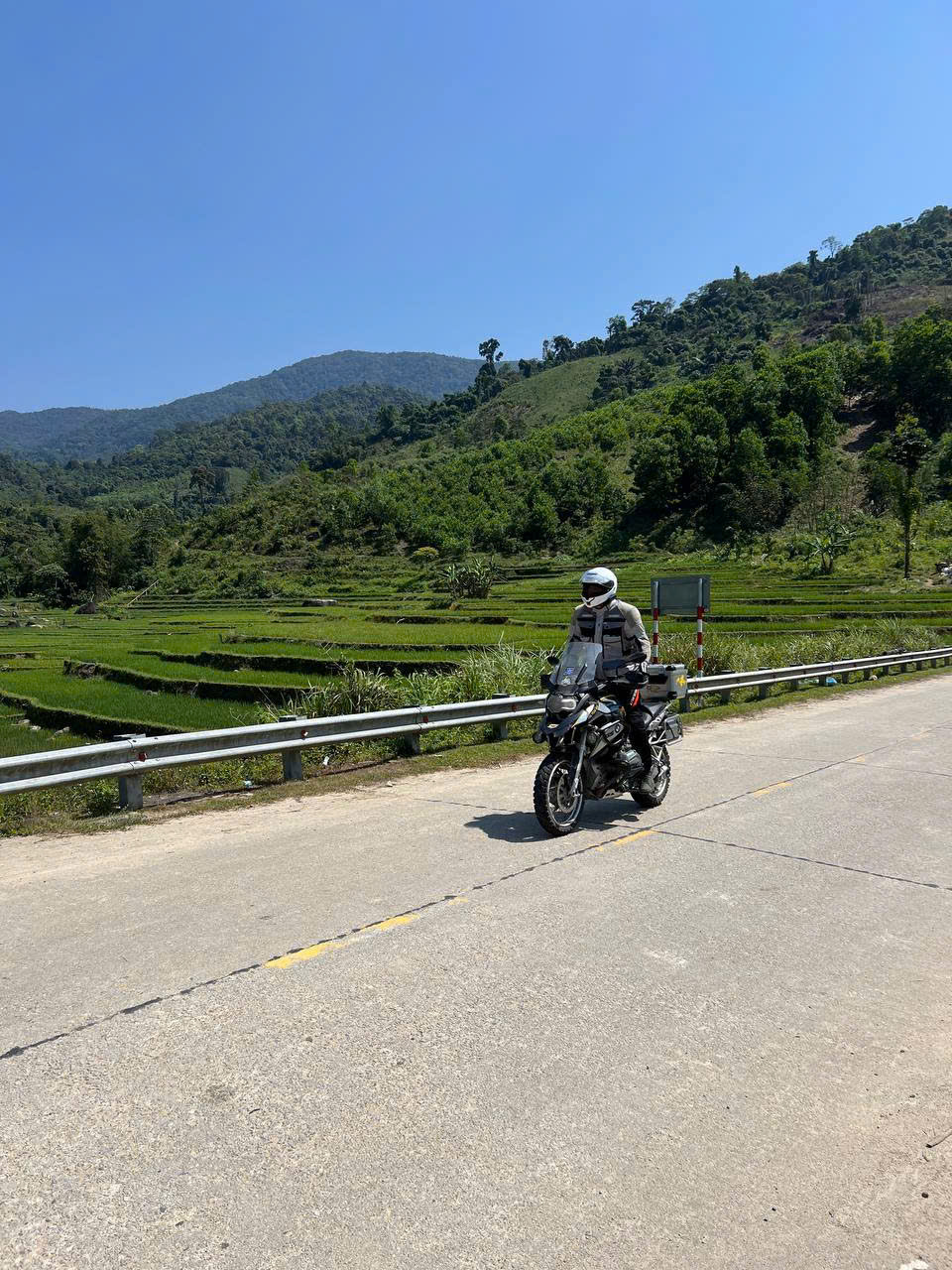 BMW GS riding past rice terraces under a blue sky