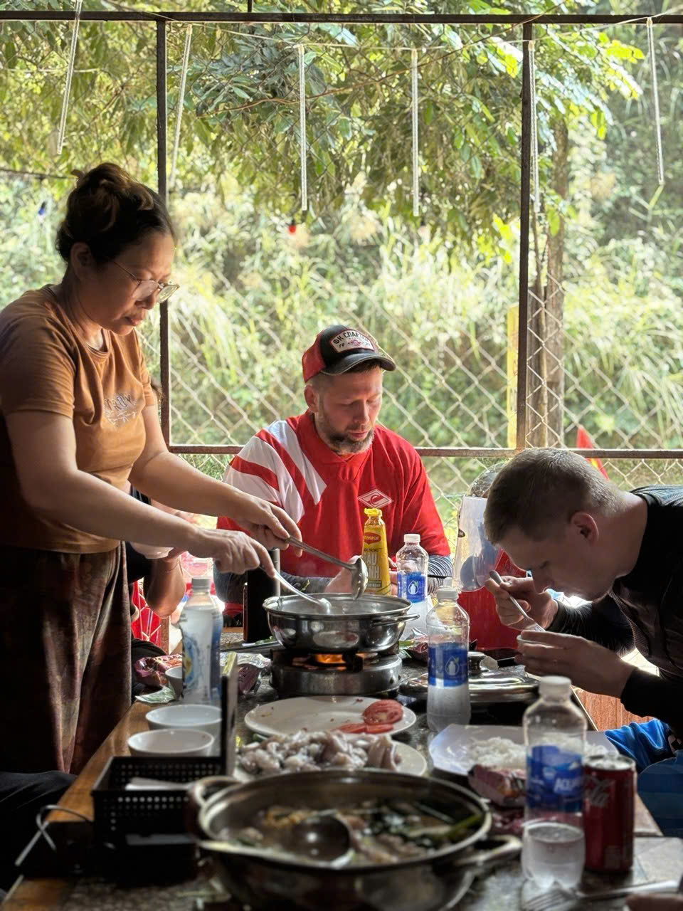 Host serving hotpot to riders at a village restaurant