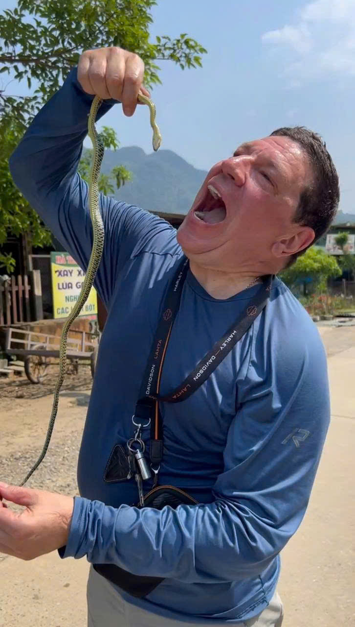 Rider pretending to swallow a small snake at a roadside stop