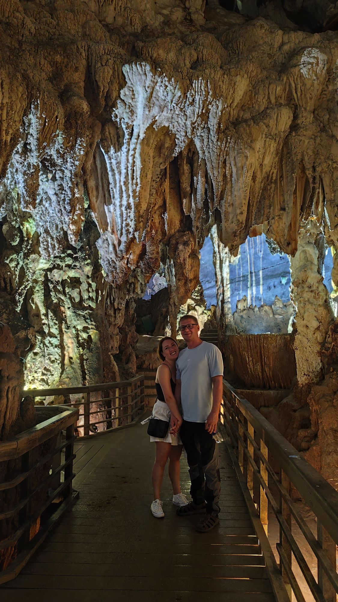 Two riders on the walkway inside a lit limestone cave