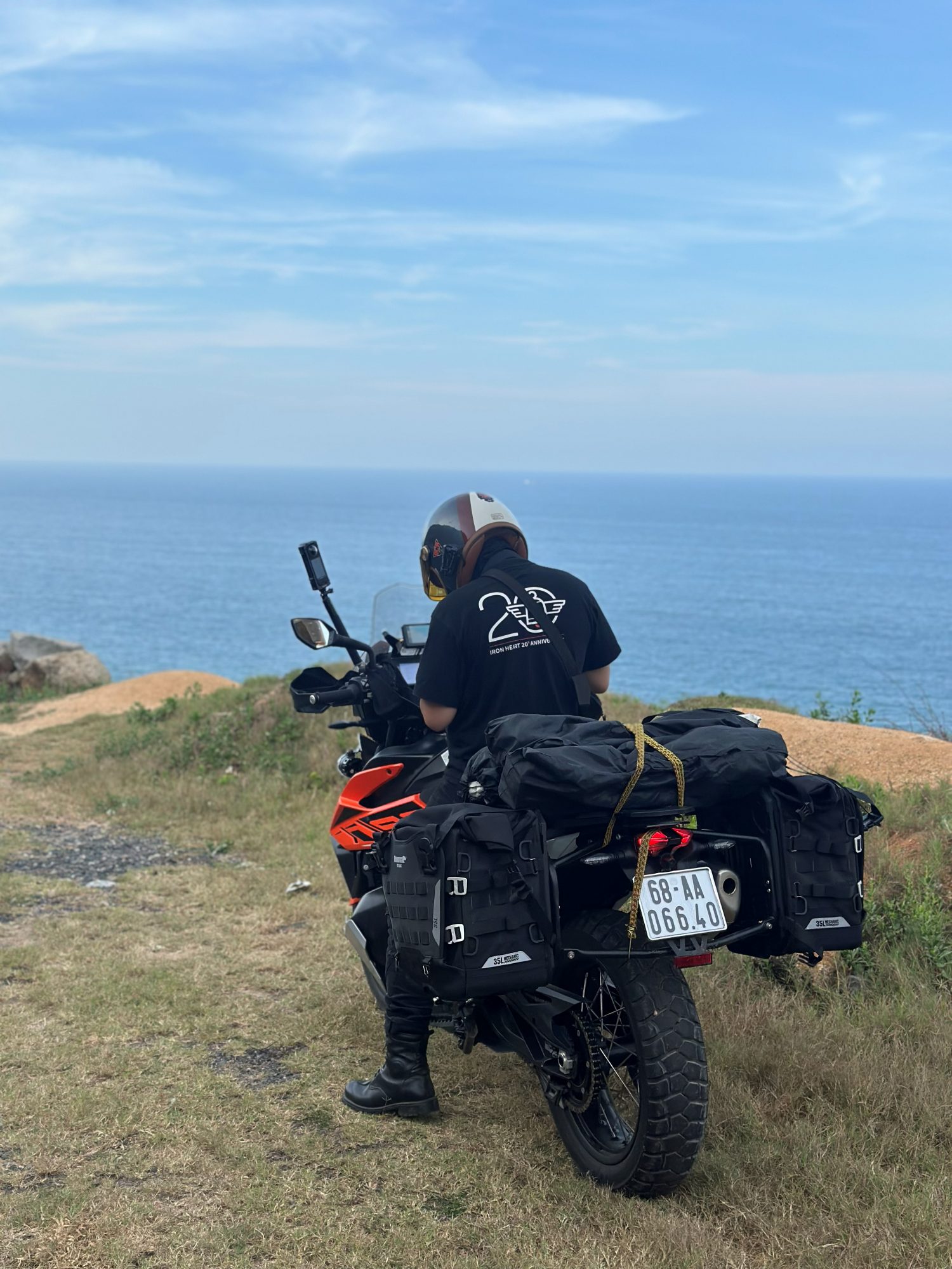 Rider with a loaded bike on a clifftop above the sea
