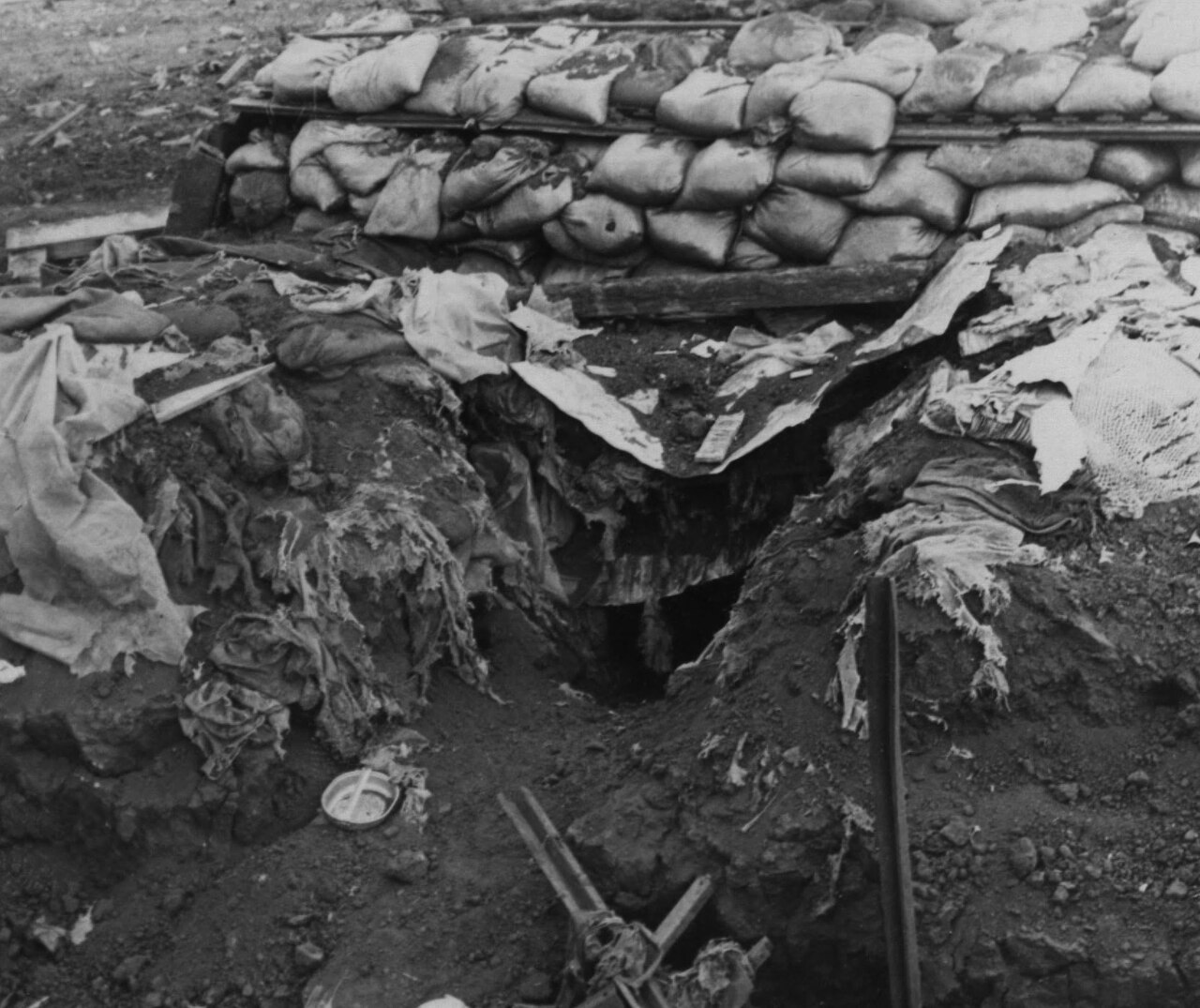 A sandbagged bunker torn open after a rocket hit, with debris around it