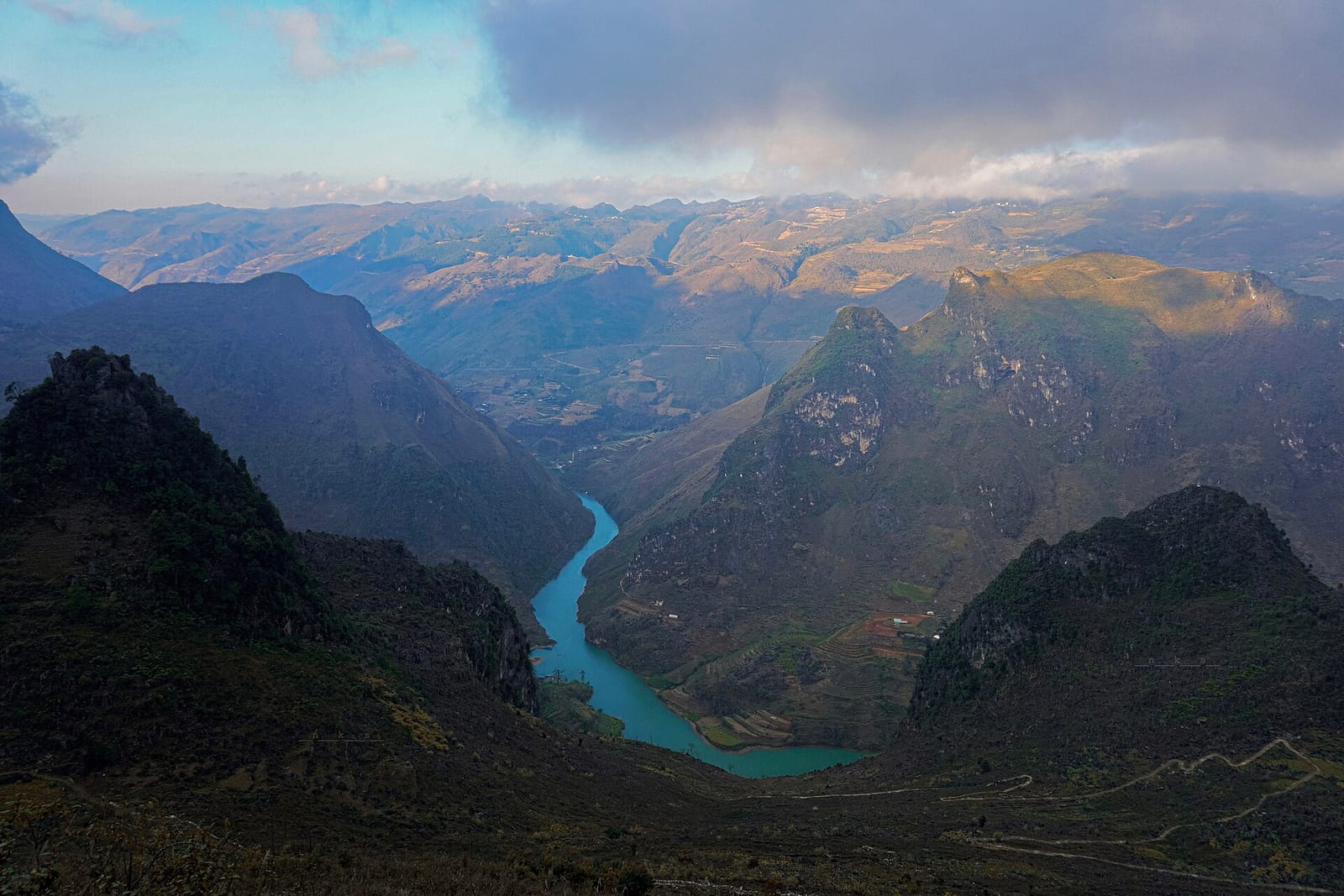 The turquoise Nho Que river winding through a deep gorge between karst mountains, seen from high above