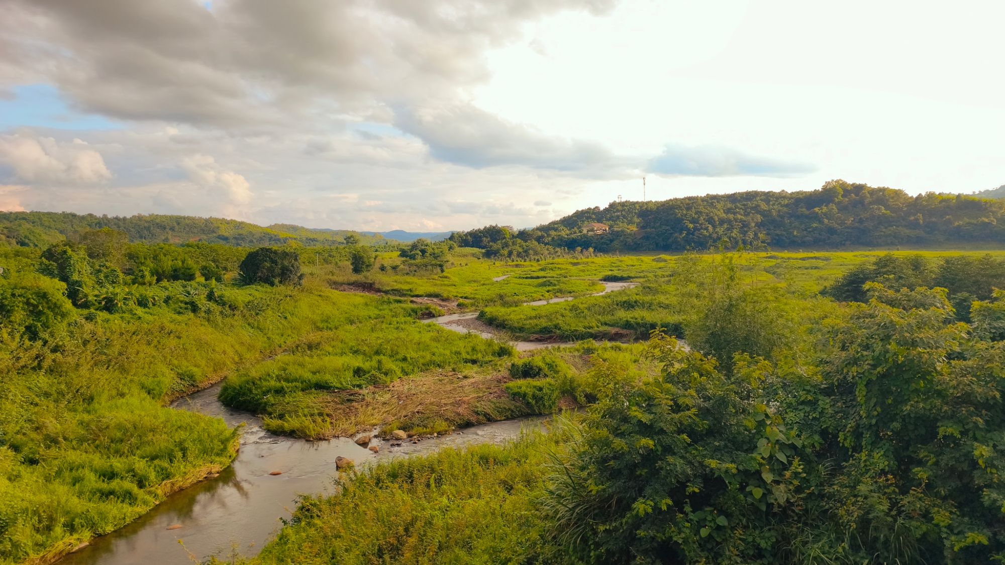 A river winding through green valleys and forested hills in Vietnam